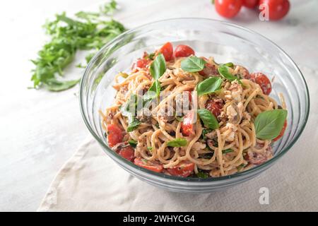 Mediterraner Partysalat aus Spaghetti mit Tomaten, Rucola, Mozzarella, Oliven und Basilikum in einer Glasschale auf weiß bemalt Stockfoto