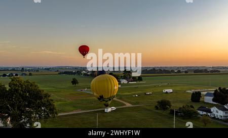 Luftaufnahme von drei Heißluftballons, die sich zum Start vorbereiten, wobei einer in der Luft schwimmt Stockfoto