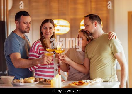 Zwei verheiratete Paare halten Gläser Champagner und toasten im Speisesaal zu Hause Stockfoto