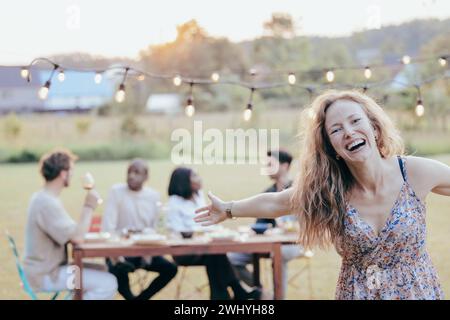 Fröhliche Blondine verzaubert Sunny Garden BBQ mit Lachen Stockfoto