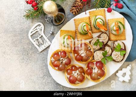 Kreative Vorspeisen setzen weihnachten. Weihnachtsbäume aus Schinken, Gurke, Käse und Karottenstern auf Crackern, Törtchen mit Hühnchen Stockfoto