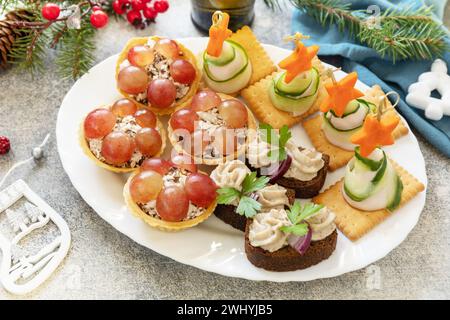 Kreative Vorspeisen setzen weihnachten. Weihnachtsbäume aus Schinken, Gurke, Käse und Karottenstern auf Crackern, Törtchen mit Hühnchen Stockfoto