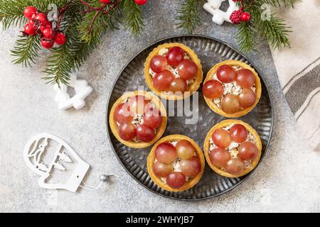 Vorspeisen zu Weihnachten. Tartlets mit Huhn und Trauben auf dem festlichen Tisch. Blick von oben. Stockfoto