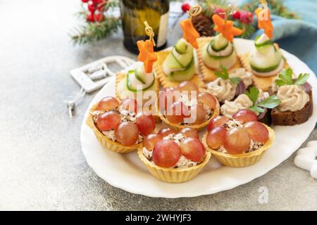 Kreative Vorspeisen setzen weihnachten. Weihnachtsbäume aus Schinken, Gurke, Käse und Karottenstern auf Crackern, Törtchen mit Hühnchen Stockfoto