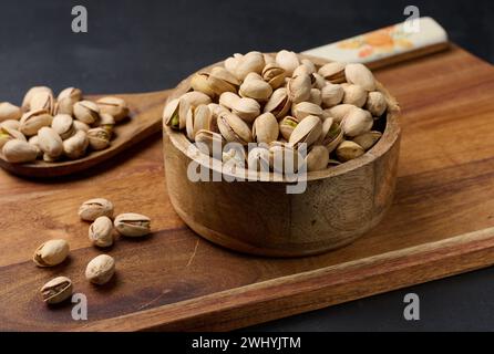 Gesalzene gebratene Pistazien in einer runden Holzschale auf dem Tisch Stockfoto