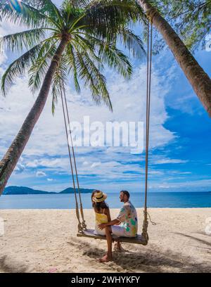 Pärchen auf einer Schaukel am Strand mit Palmen in Phuket Thailand Stockfoto