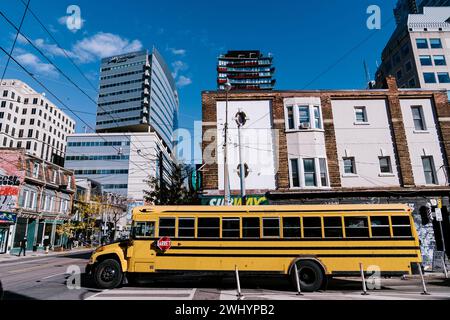 Toronto, Kanada - 28. Oktober 2023: Eine pulsierende Stadtstraße mit einem gelben Schulbus im Vordergrund, der ältere Brick kontrastiert Stockfoto