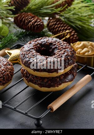 Schokoladen-Donuts, bestreut mit zerquetschten Nüssen auf einem schwarzen Tisch Stockfoto