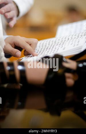 Junger Mann, der vor der Bar-Mitzwa-Feier die Thora liest. Ich trage Tefillin auf der rechten Seite. Stockfoto