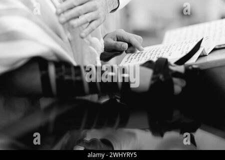 Junger Mann, der vor der Bar-Mitzwa-Feier die Thora liest. Ich trage Tefillin auf der rechten Seite. Stockfoto