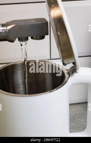 Gießen Sie sauberes gefiltertes Leitungswasser in einen elektrischen Wasserkocher für kochendes Wasser in der Küche, sauberes Wasser für die Gesundheit Stockfoto