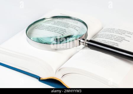 Öffnen Sie das Buch und die Lupe auf weißem Hintergrund aus nächster Nähe Stockfoto