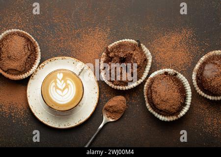 Schokolade und Kakao bräunliche Muffins mit Kaffee Cappuccino in der Tasse von oben Blick auf braunen rustikalen Stein Hintergrund, süße hausgemachte dunkle Stockfoto