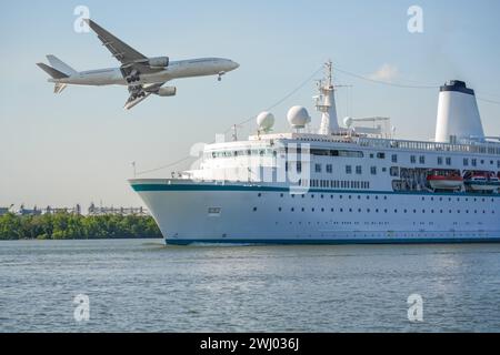 Das Kreuzfahrtschiff geht ins offene Meer, Flugzeuge fliegen zu einem Meeting, während sie abends bei Sonnenuntergang am Horizont des Flughafens landen. Urlaub im Sommer Stockfoto