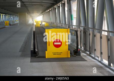 Gelber Zaun mit gemauertem Schild, Passage für Reisende verboten, erhöhter Fußgängerübergang am Flughafen, Bahnhof Stockfoto