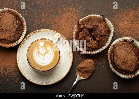 Schokolade und Kakao bräunliche Muffins mit Kaffee Cappuccino in der Tasse von oben Blick auf braunen rustikalen Stein Hintergrund, süße hausgemachte dunkle Stockfoto