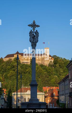 Die Dreifaltigkeitssäule, das Schloss von Ljubljana und das Gebäude der slowenischen Philharmonie bei Sonnenuntergang in der Stadt Ljubljana, Slowenien. Stockfoto