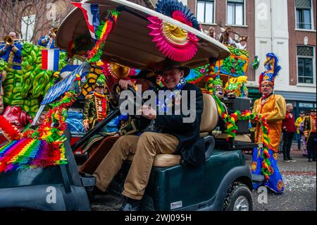 Nijmegen, Niederlande. Februar 2024. Zwei alte Männer werden gesehen, wie sie ein kleines Auto fahren, das für den Karneval dekoriert ist. In Nijmegen, Niederlande, besteht die Karnevalsparade aus einem Wagen, der von einem Elektrofahrzeug mit den Prinzen und Prinzessinnen des Jahres gezogen wird. Der Rest der Parade besteht aus Personen, die in bunten Kostümen und Musikbands gekleidet sind. Die Hauptattraktion jedes Jahr ist das Kostüm, das der Bürgermeister der Stadt Huber Bruls trägt, dieses Jahr war das Thema Flower Power. Quelle: SOPA Images Limited/Alamy Live News Stockfoto