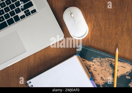 Laptop, Weltkarte und Notebook auf einem Holztisch, Draufsicht. Stockfoto