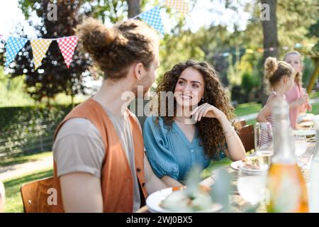 Porträt eines Paares am Tisch mit Familie und Freunden auf der Familiengartenparty. Stockfoto