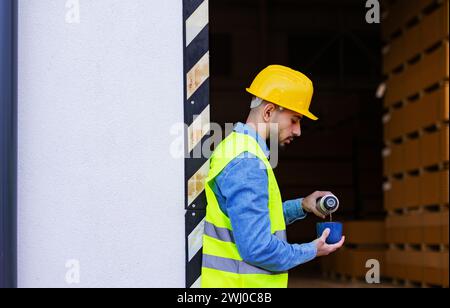 Porträt des Arbeiters, der sich von der Arbeit aufhält, Kaffee trinkt, Tee gießt, sich ausruhen, auf der Laderampe steht, im Freien. Stockfoto