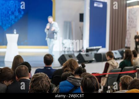 Das Publikum hört einem Sprecher aufmerksam zu, der während einer professionellen Konferenz im Hintergrund verschwimmt. Stockfoto