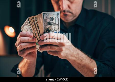 Ein gut gekleideter Geschäftsmann, der amerikanische Dollar am Schreibtisch zählt, selektiver Fokus Stockfoto