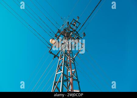 Strommast mit Oberleitungen und Straßenlaterne vor blauem Himmel Stockfoto