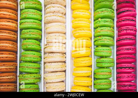 Verschiedene bunte Macarons oder französische Makronen hintereinander, süße Süßigkeiten auf Baisuebasis mit Eiweiß, Puderzucker, Kristallzucker. Hohe Qualität Stockfoto
