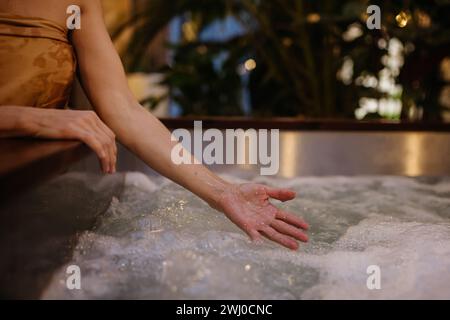 Nahaufnahme einer Frau, die am Whirlpool steht, Wasser spritzt, Wellness-Wochenende im Spa genießt. Stockfoto