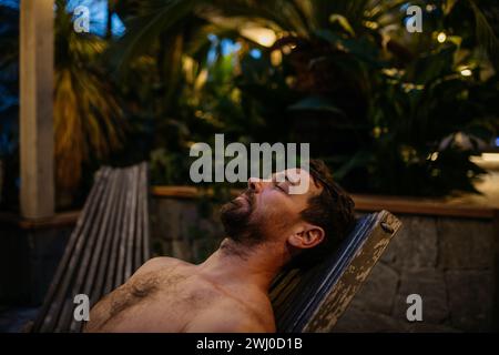 Gutaussehender Mann, der auf der Liege liegt und sich mit geschlossenen Augen entspannt. Wellnesswochenende im Spa für Mann. Stockfoto