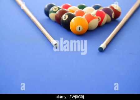 Billard-Kugeln und Billard-Queue sind an einem sonnigen Sommertag im Freien auf dem blauen Billard-Tisch. Queue auf dem Tisch, kurz vor dem Ball, Bokeh-Foto Stockfoto