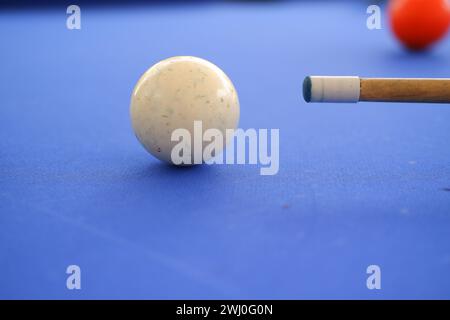 Billard-Kugeln und Billard-Queue sind an einem sonnigen Sommertag im Freien auf dem blauen Billard-Tisch. Queue auf dem Tisch, kurz vor dem Ball, Bokeh-Foto Stockfoto