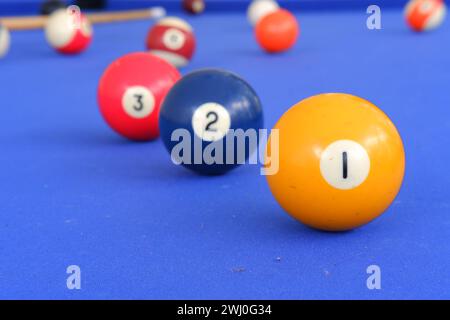 Billard-Kugeln und Billard-Queue sind an einem sonnigen Sommertag im Freien auf dem blauen Billard-Tisch. Ball mit der Nummer 1 vorne Stockfoto