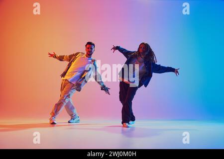 Zwei Tänzer, Mann und Frau, die in Bewegung vor dem Hintergrund des Gradient-Studios tanzen. Dynamische Bewegung. Stockfoto