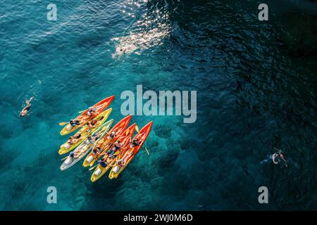 Touristen schwimmen im türkisfarbenen Meer in der Nähe eines Teams von Kajakfahrern in Kajaks. Drohne Stockfoto