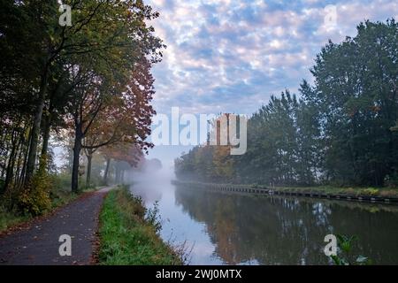 Herbstliche Gelassenheit: Kanal Im Herbstlaub Unter Wolkengeküsstem Himmel Stockfoto