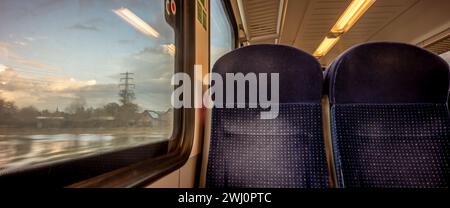 Leere Fahrgastsitze im niederländischen Eisenbahnabteil mit großer Fensterlandschaft. Öffentliche Verkehrsmittel in der Busklasse. Stockfoto