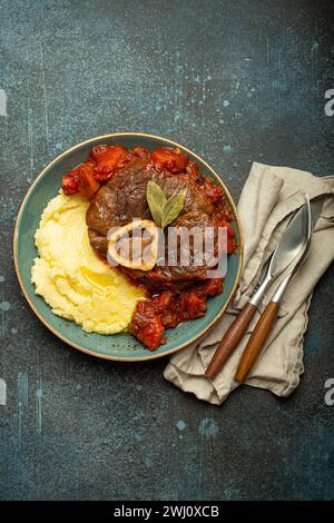 Traditionelles italienisches Gericht Ossobuco ganz Milanese mit geschnittenem Kalbsfleisch mit Tomatensoße serviert mit Maispolent Stockfoto