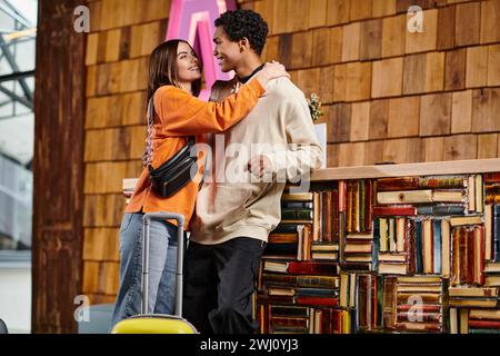 Verschiedene Paare teilen sich eine warme Umarmung in einer gemütlichen Bibliothek, umgeben von Regalen mit Büchern und Koffern Stockfoto