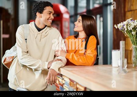 Glücklicher schwarzer Mann und eine Frau, die ein Gespräch genießen, während sie an der Rezeption im Hostel stehen Stockfoto