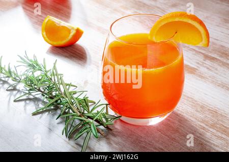 Frisches Orangengetränk mit Rosmarin auf hölzernem Hintergrund, Cocktail oder Mocktail Stockfoto
