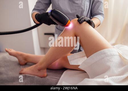 Schuss einer jungfit brünetten Klientin, die eine Laser-Haarentfernung am Körper erhält Stockfoto