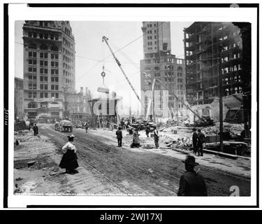 Erdbeben In San Francisco 1906. Sehen Sie nach Erdbeben und Feuer, wie ein Kran Schutt bewegt, während mehrere Männer und eine Frau vorbeifahren. Stockfoto