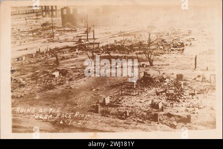 TULSA RACE RIOT (31. Mai und 1. Juni 1921): Eine sepiafarbene Fotopostkarte, die den zerstörten Stadtteil Greenwood in Tulsa, Oklahoma nach dem Tulsa Race Massaker darstellt. Aus einer erhöhten Position heraus zeigt das Bild Blöcke von Häusern und Unternehmen, die in Trümmern versenkt waren. Im rechten Vordergrund sind mehrere verkohlte Metallbetten zu sehen. In der Mitte des Bildes verläuft eine Linie verkohlter Bäume. Oben links, auf der anderen Seite einer breiten Allee, stehen einige leere Backsteinfassaden. In der unteren linken Ecke, in das negative geschrieben und als weißer Text erscheint [RUINS OF THE / TULS Stockfoto