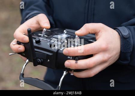 LVIV, UKRAINE - 11. Februar 2024: Ein junger Mann wird während eines selbstgesteuerten Flugtrainings mit einer Fernbedienung gesehen, die den Flug einer FPV-Drohne steuert Stockfoto