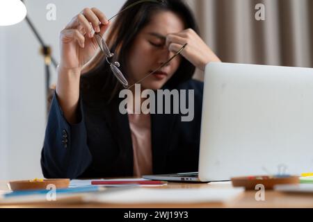 Junge Frau, die lange Zeit vom Sitzen und Arbeiten am Computer gestresst war Stockfoto