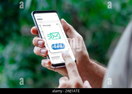 Ein Mann, der gerade eine Nachricht mit seinem Handy sendet. Digitales Kommunikationskonzept. E-Mail, Textnachricht, sms. Stockfoto