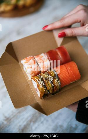 Sushi-Set auf Packbox in der Hand verschiedene japanische Sushi-Rollen Stockfoto