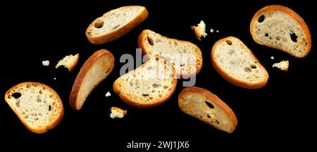 Fallende Bruschetta-Cracker, runde Brotcroutons isoliert auf schwarzem Hintergrund Stockfoto